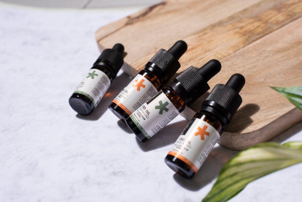 ours-journey CBD oil bottles arranged on a wooden board with a natural leaf, perfect for holistic product promotion.